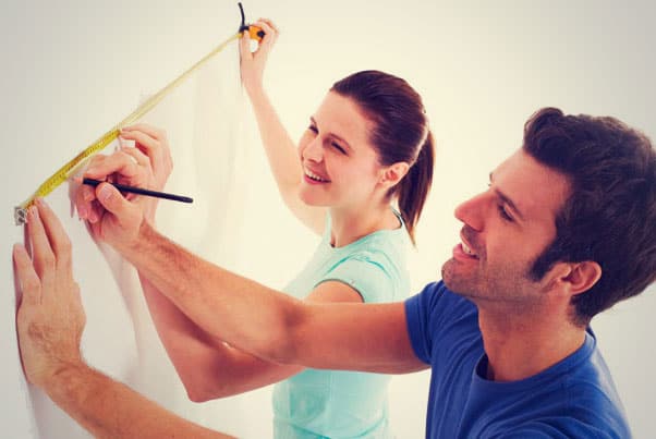 A couple trying to measure wall size to buy roller shutters